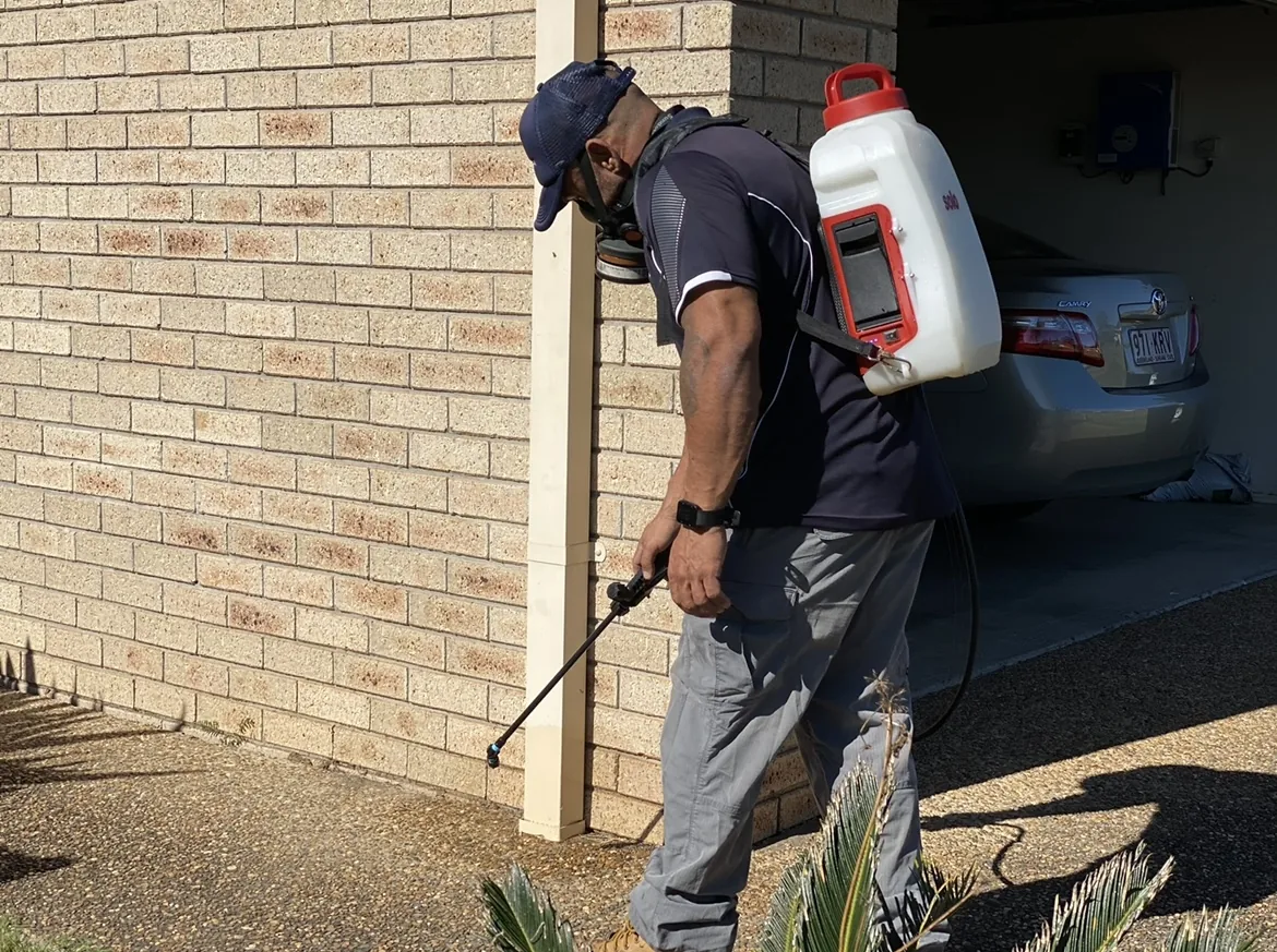 Technician applying an exterior pest control treatment at a residential property