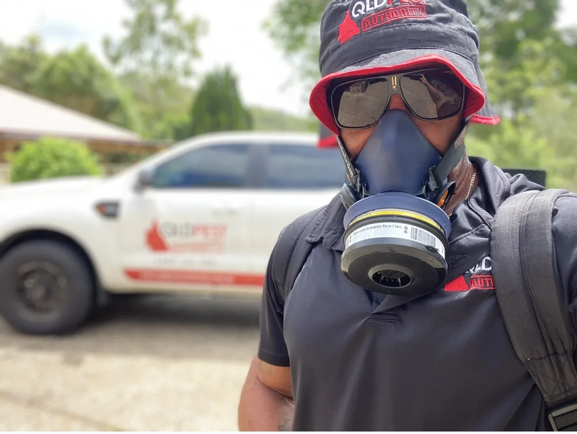 QLD Pest Authority technician wearing protective equipment with branded work vehicle